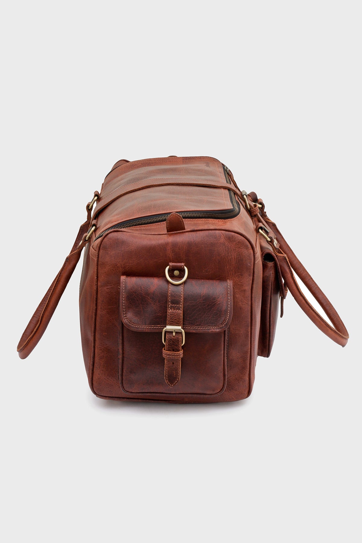 Side profile of the Cognac duffel bag with buckled flap pocket