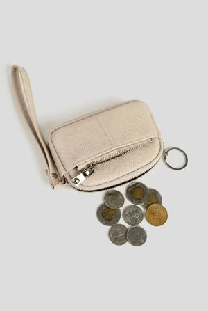 Beige coin pouch wristlet shown with loose coins to show capacity